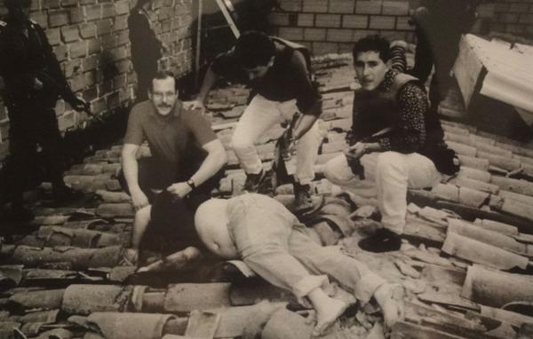Pablo Escobar está tendido muerto en un tejado. Un agente de la DEA y policías colombianos posan junto al cuerpo del zar de la cocaína