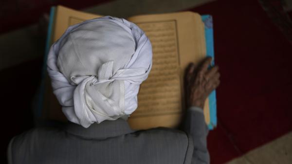 Un hombre lee versos del Corán, el libro sagrado del islam, en el primer día del mes de ayuno del Ramadán en la Gran Mezquita de la ciudad vieja de Sanaa, Yemen (AFP)