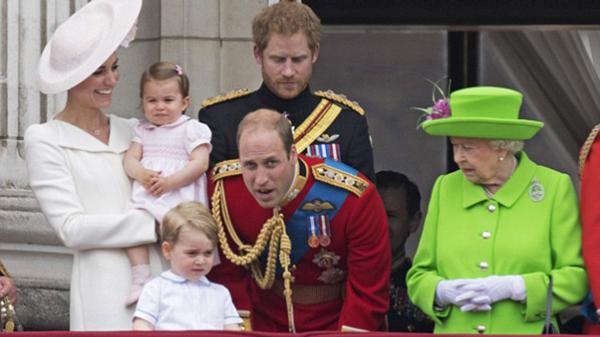 El príncipe William se agacha para hablar con su pequeño hijo, George. La reina Isabel observa el movimiento