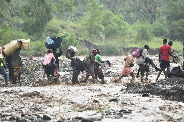 Los haitianos intentan cruzar el rio La Digue a pie ya que el puente colapsó por los fuertes vientos