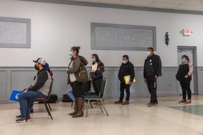 Inmigrantes con mascarillas esperan en una fila para recibir sus nuevos pasaportes en el consulado de EEUU (Foto: Reuters)