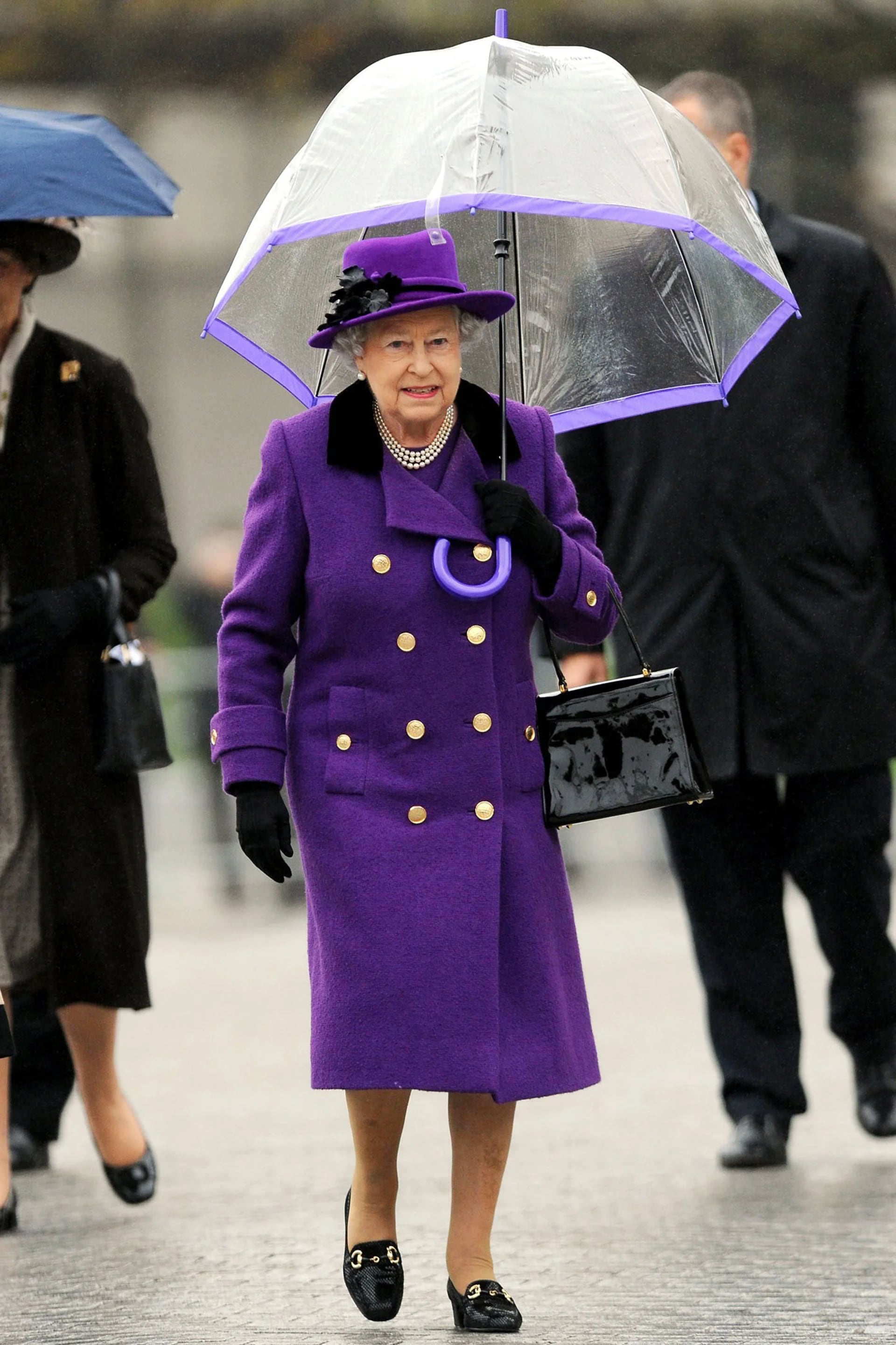 Con un vestido look en violeta y el paraguas transparente envivado en lila, pasea bajo la lluvia londinense