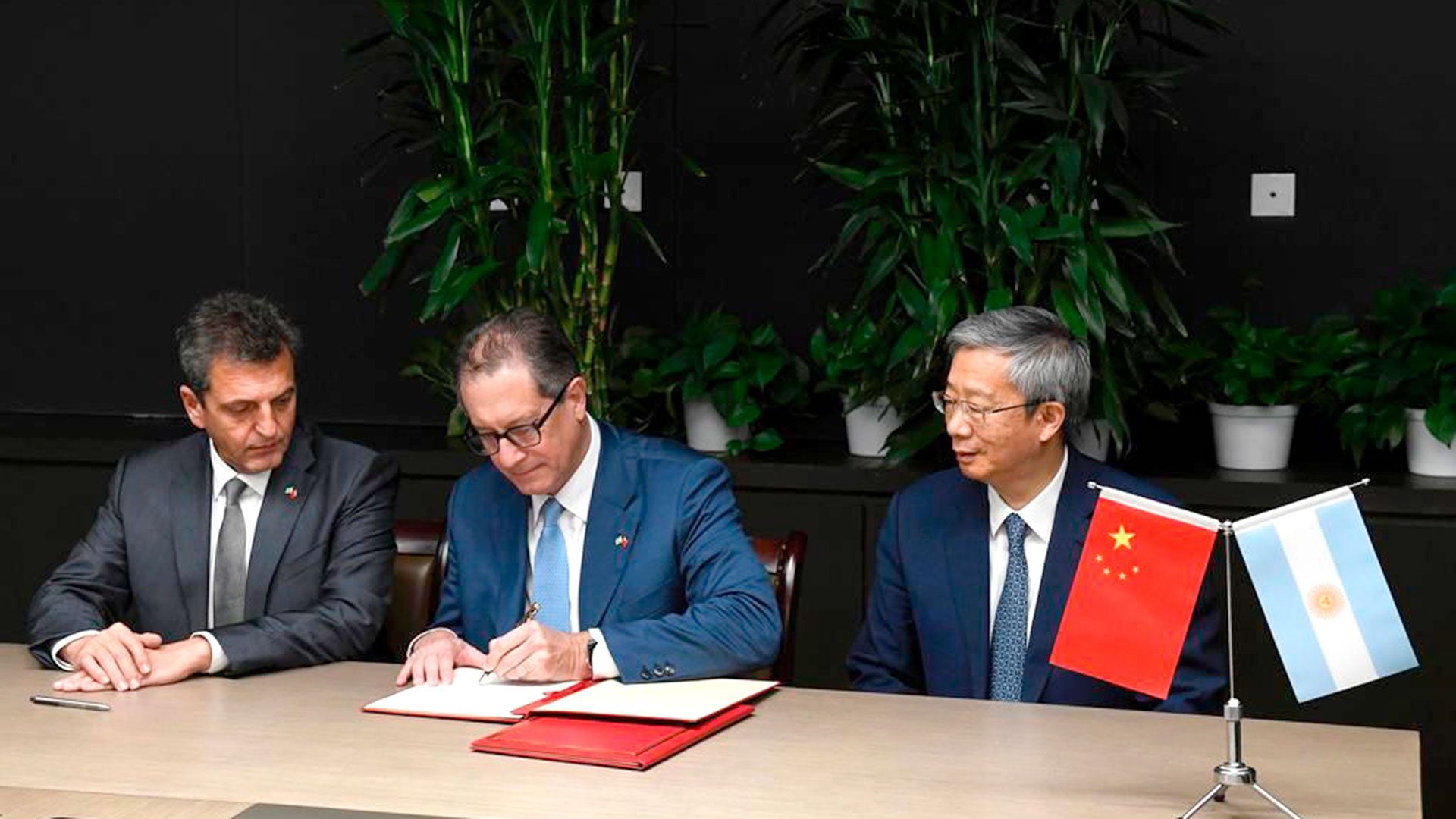 El presidente del BCRA, Miguel Pesce, entre su par de China, Yi Gang, y el ministro Sergio Massa, firmando la ampliación del uso del canje de monedas con China