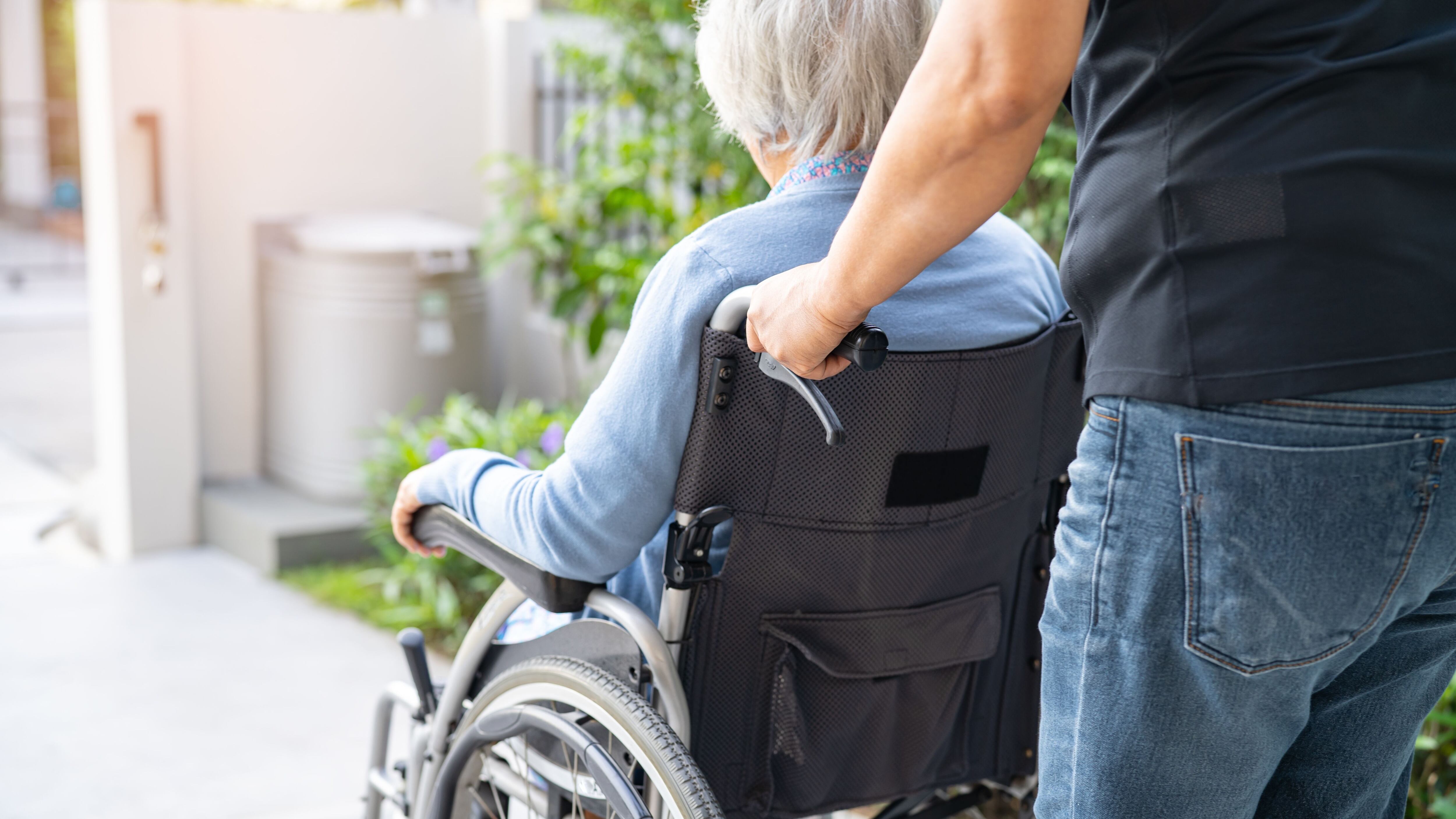 Un hombre empuja la silla de ruedas de una mujer con Parkinson (Shutterstock)