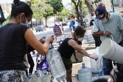 FOTO DE ARCHIVO. Imagen referencial de personas recolectando agua en una calle, en Caracas, Venezuela. 23 de marzo de 2020. REUTERS/Manaure Quintero