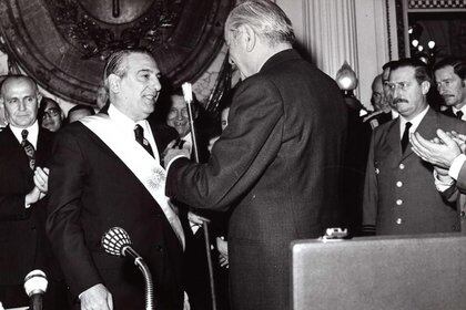 Hector Cámpora entrega el bastón presidencial a Raúl Lastiri. A la izquierda Llambí observa con seriedad, en el medio José Ber Gelbard sonríe
