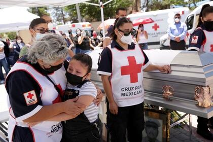 Paramédicos de Cruz Roja participan en el funeral de su compañero Andrés García González, quien trabajaba como enfermero del IMSS y murió por coronavirus, en la imagen se ve a su hija Sofía acompañada de su abuela Bertha en Ciudad Juarez Foto: (REUTERS/Jose Luis Gonzalez)