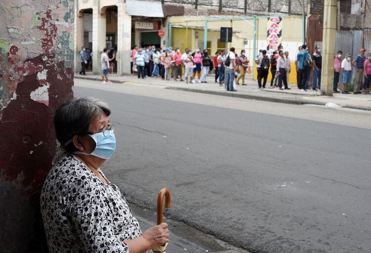 Foto de archivo . Una mujer espera frente a la calle donde ancianos esperan para cobrar su pensión mensual antes del toque de queda impuesto por el gobierno para prevenir la propagación de la enfermedad por coronavirus (COVID-19), en Guayaquil, Ecuador. 20 de marzo de 2020. REUTERS/Santiago Arcos