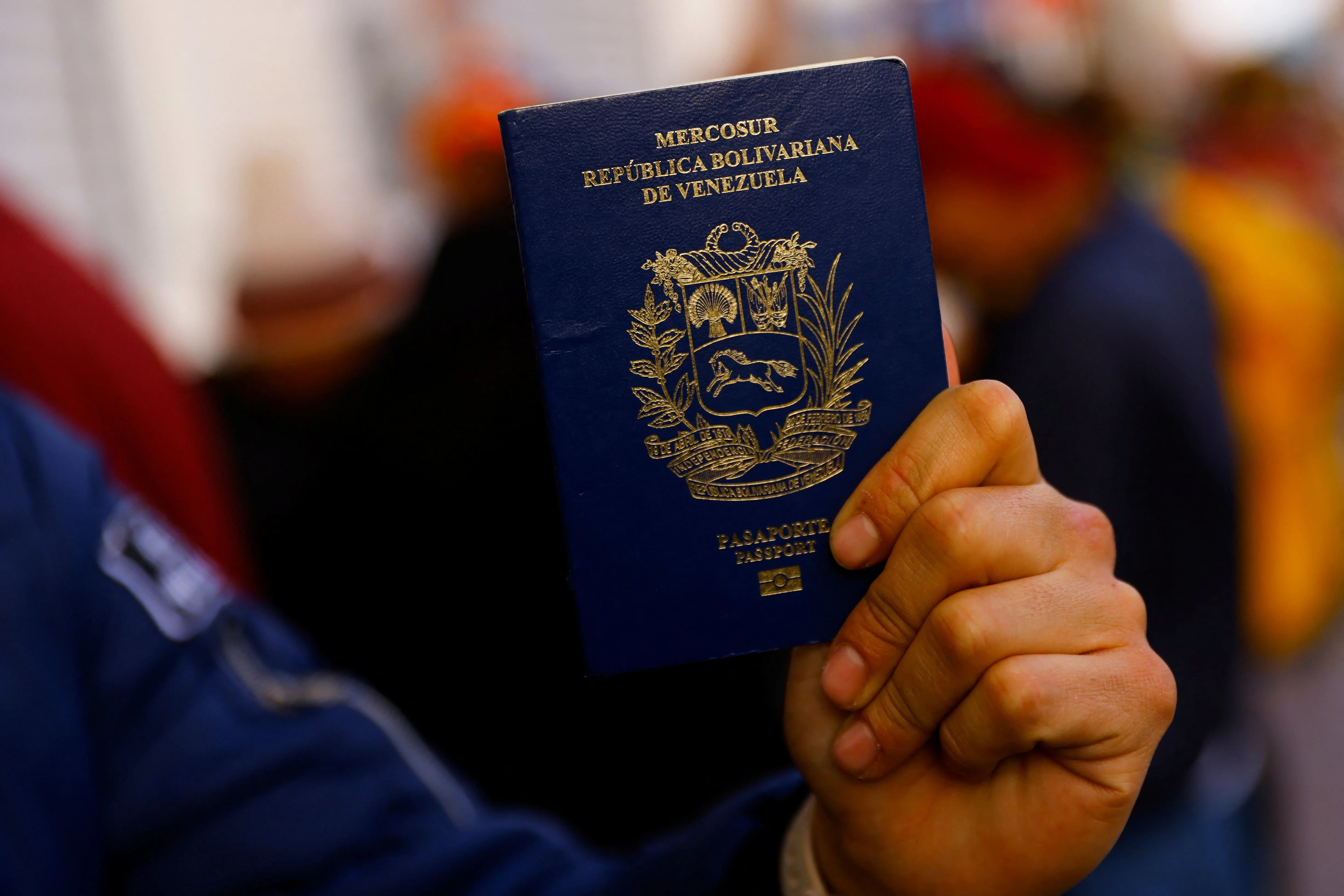 Un migrante de Venezuela muestra su pasaporte mientras hace cola para pasar la noche en un almacén en el centro de Ciudad Juárez, México (REUTERS/José Luis González)
