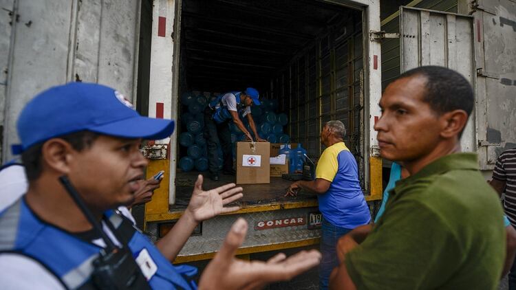 En el barrio de Catia, en Caracas, cooperantes de la Cruz Roja entregaron bidones para el acopio de agua así como pastillas potabilizadoras (AFP)