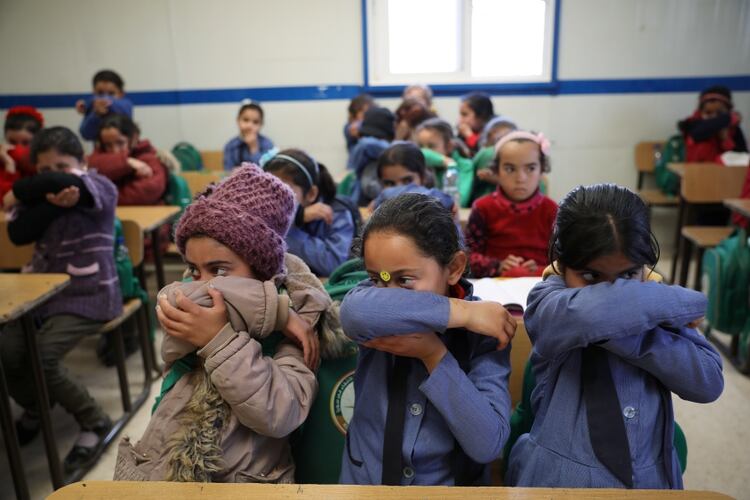 Niños refugiados sirios aprenden la forma correcta de cubrirse para estornudar y toser ante la amenaza de coronavirus 