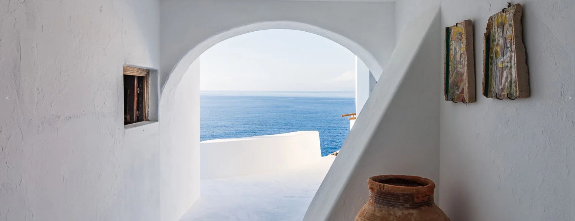 Las casas blancas ubicadas a lo largo de la costa, contrastan con la vegetación verde y el mar azul profundo