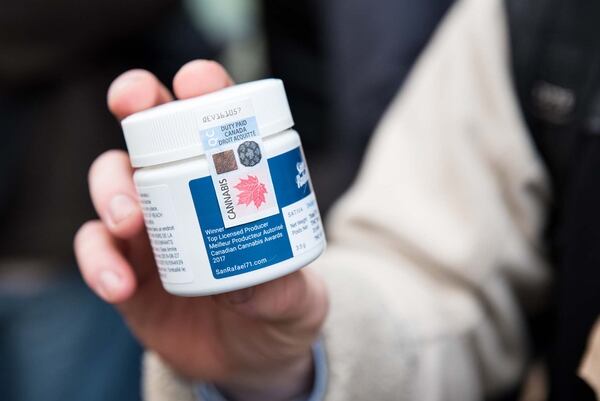 Un comprador muestra el envase con marihuana que compró apenas activada la legalización (MARTIN OUELLET-DIOTTE / AFP)