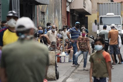 Personas hacen fila para llenar contenedores con agua de un grifo de incendios en Caracas