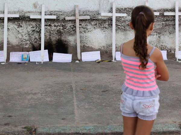 Foto de archivo: Una niña observa las flores y pancartas colocadas frente a la escuela Tasso da Silveira, donde un hombre armado abrió fuego contra los alumnos, en Río de Janeiro el 9 de abril de 2011 (REUTERS)