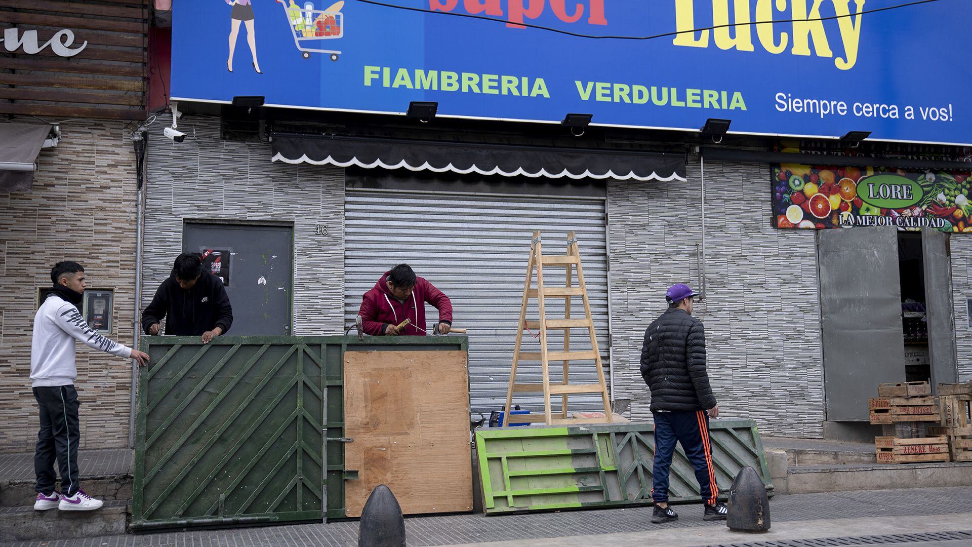 El propietario de un supermercado, Roger Oscosivi (centro), suelda una puerta de metal reforzado en la entrada de su tienda después de amenazas de saqueo en Loma Hermosa, en el municipio de Tres de Febrero (AP Photo/Victor R. Caivano)