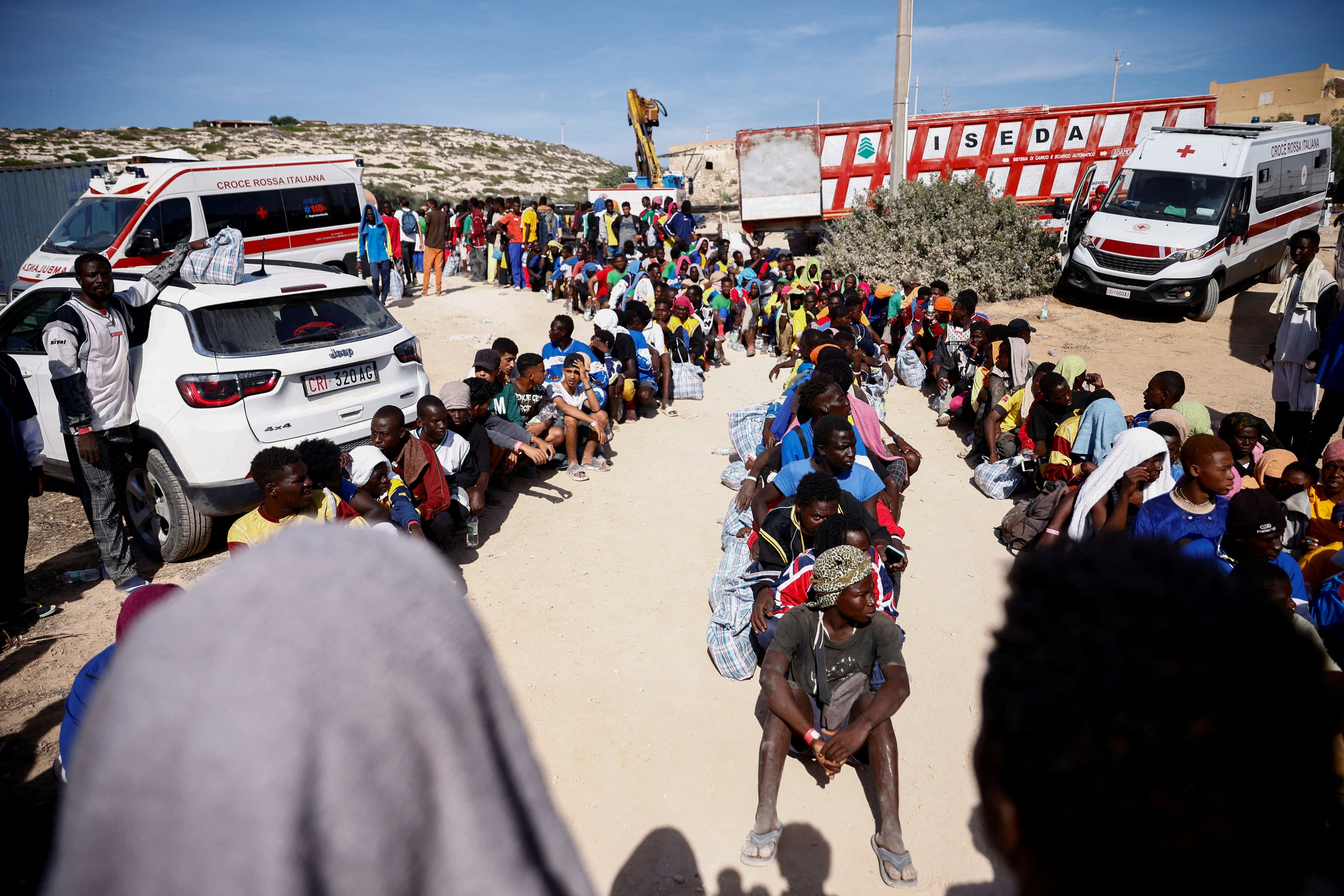 Migrantes hacen cola mientras esperan a ser trasladados en la isla siciliana de Lampedusa. (REUTERS/Yara Nardi)