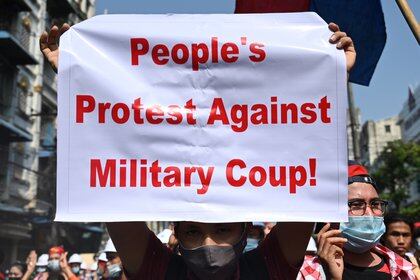 A protester holds up a sign during a demonstration against the military coup in Yangon on February 6, 2021. (Photo by YE AUNG THU / AFP)