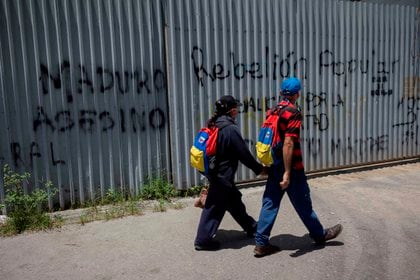 Dos personas caminan ante varios grafitis con mensajes de rechazo al presidente de Venezuela, Nicol&#225;s Maduro, en Caracas (Venezuela).EFE/ Rayner Pe&#241;a
