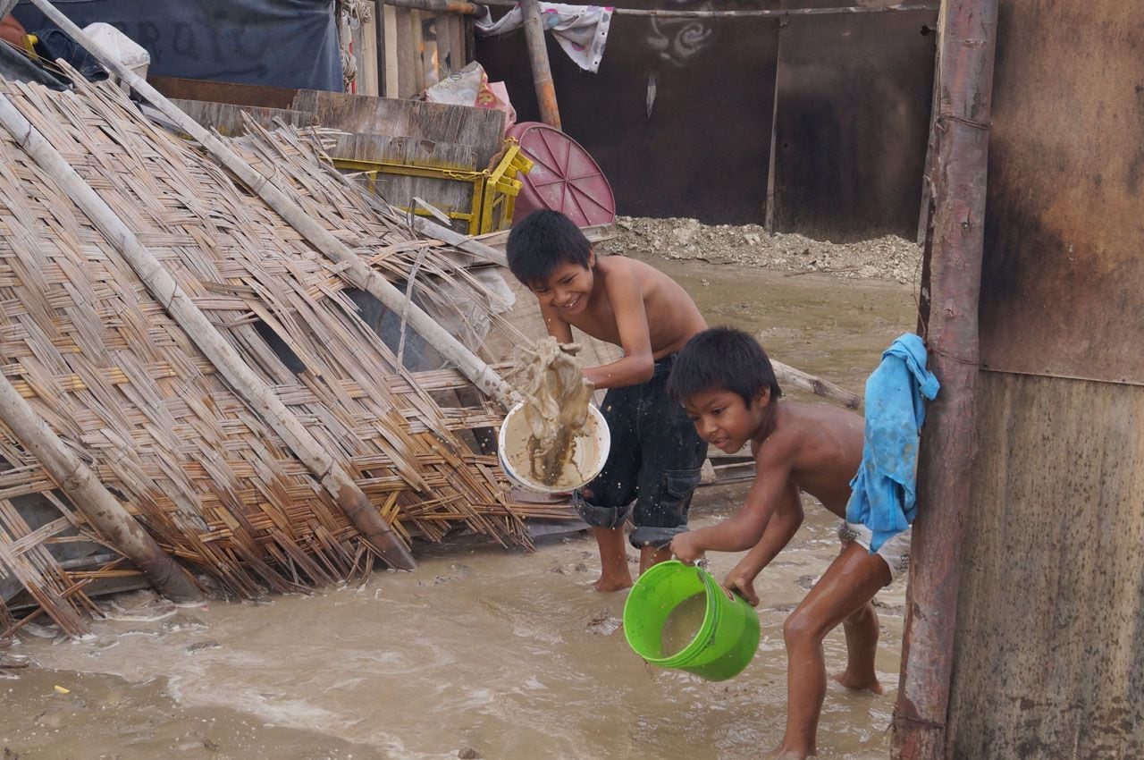 En la adversidad ocasionada por el Niño Costero, dos menores piuranos se suman a las acciones de limpieza e intentan con baldes sacar el agua empozada de sus casas. (Walter Méndez Cano)