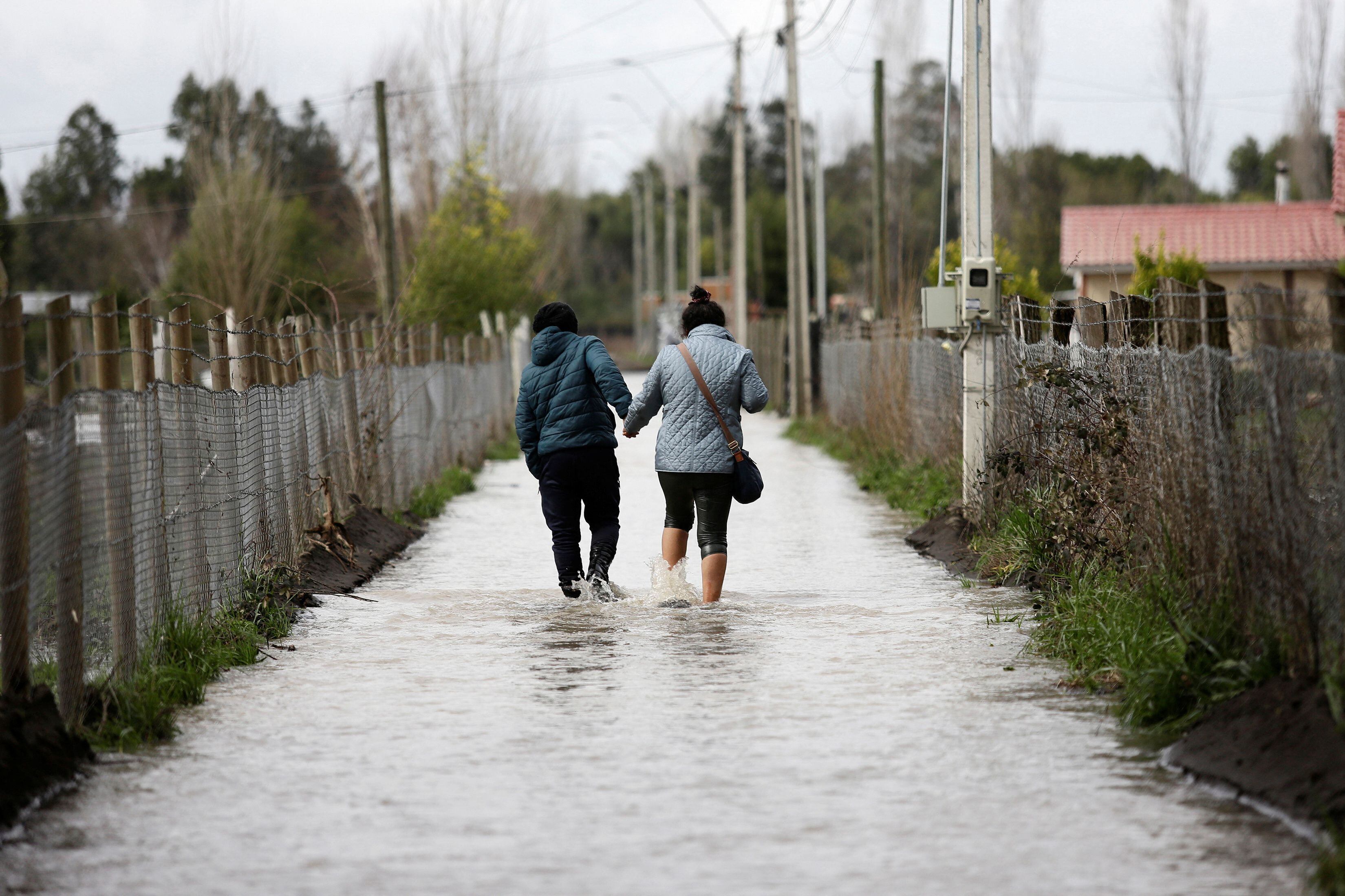 Dos jóvenes se ayudan a caminar en la calle inundada (REUTERS/Juan Gonzalez)