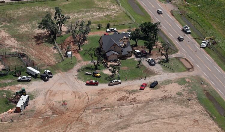 Las cuadrillas comienzan a reemplazar las líneas eléctricas a través de una casa dañada por un tornado, el martes 21 de mayo de 2019, cerca de Mangum, Oklahoma (AP)