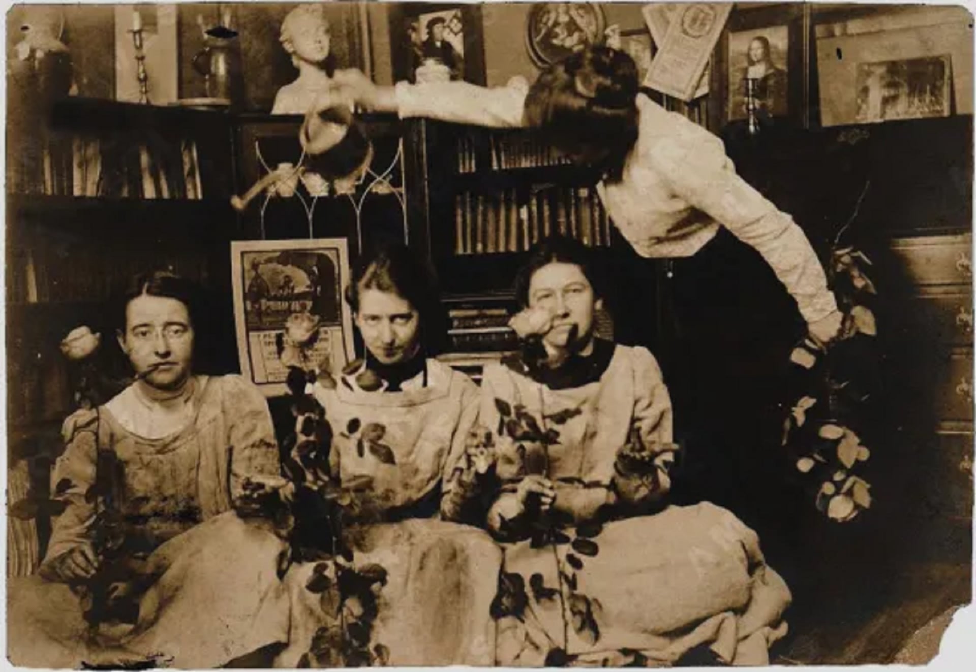 Green, Oakley y Smith sentadas, cada una sosteniendo una rosa, mientras Cozens sostiene una regadera sobre sus cabezas (Foto: Wikipedia)