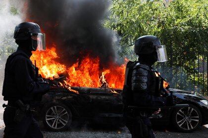 French CRS riot police officers walk past a burning car during a demonstration of the yellow vests movement in Paris, France September 12, 2020. REUTERS/Gonzalo Fuentes