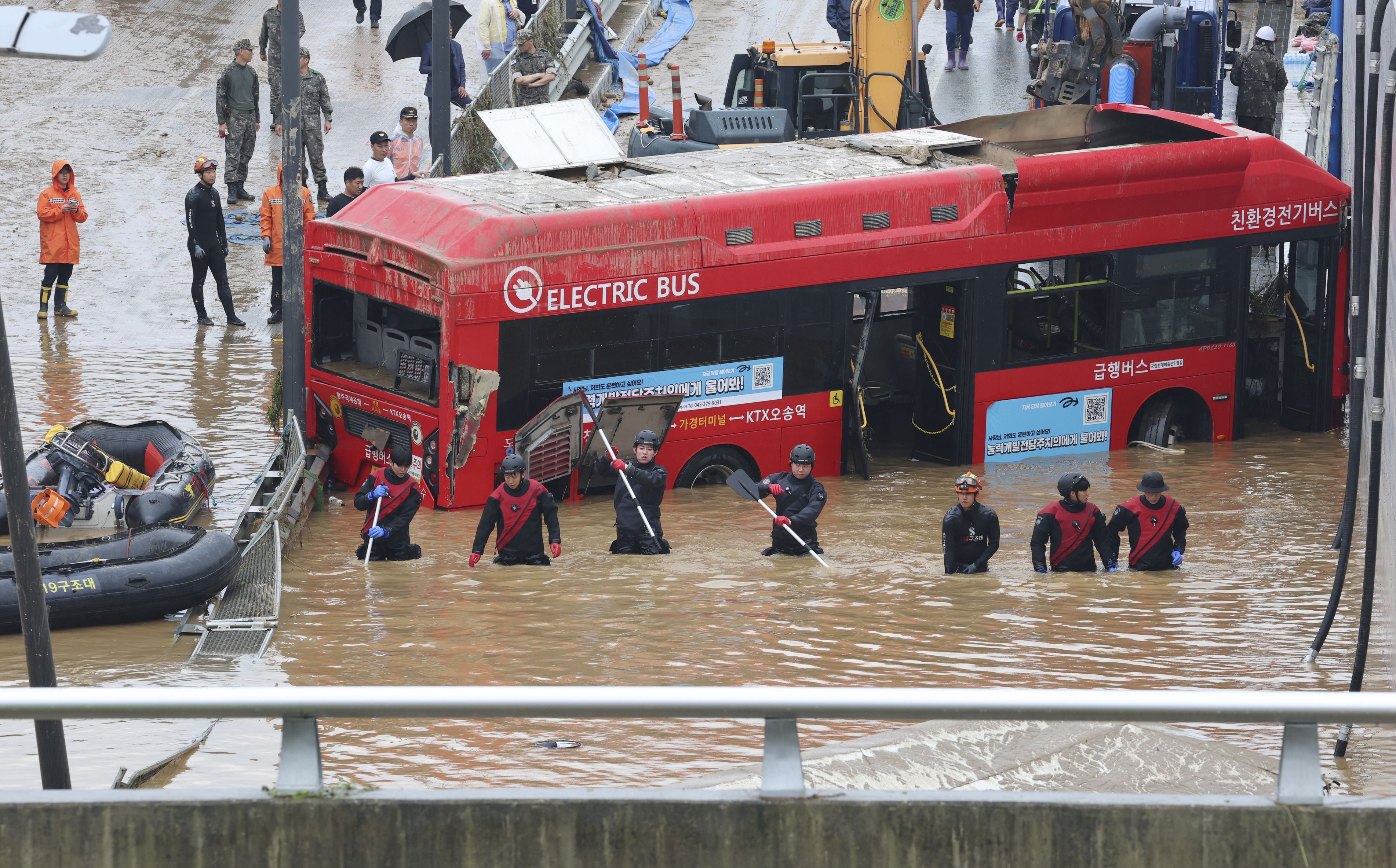 Rescuers search for survivors along a road submerged by floodwaters leading to an underground tunnel in Cheongju, South Korea, Sunday, July 16, 2023. Days of heavy rain triggered flash floods and landslides and destroyed homes, leaving scores of people dead and forcing thousands to evacuate, officials said Sunday. (Kim Ju-hyung/Yonhap via AP)