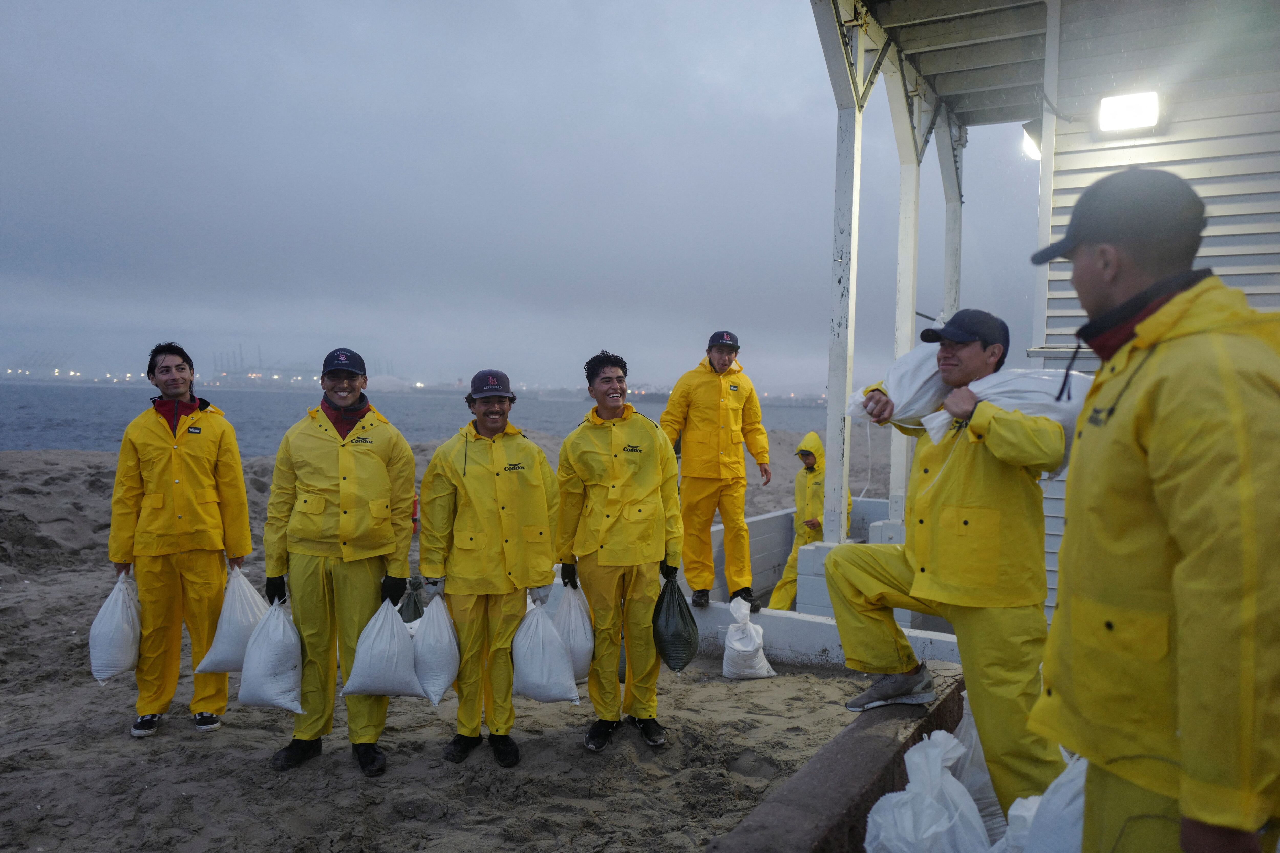 Los socorristas jóvenes se alinean para tomarse una foto frente a su sede en Long Beach mientras la tormenta tropical Hilary avanza por el sur de California.