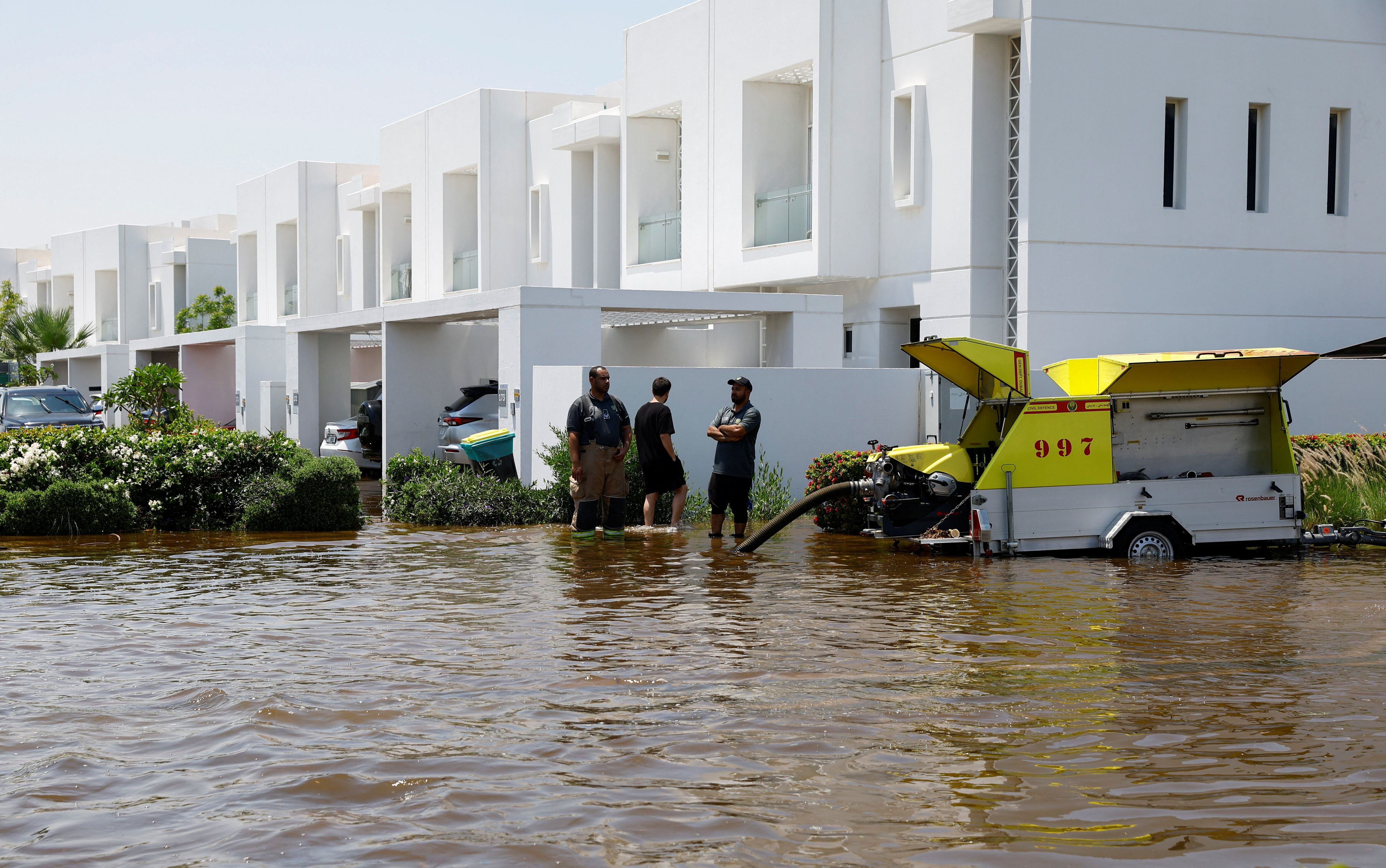 Los miembros del equipo de bomberos y rescate se encuentran junto a un camión que bombea agua que se ha acumulado debido a las fuertes lluvias, en una comunidad residencial en Dubai, Emiratos Árabes Unidos, el 18 de abril de 2024. REUTERS/Rula Rouhana