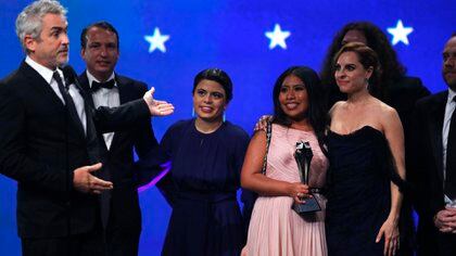 El director Alfonso Cuarón le hace un gesto a la actriz Yalitza Aparicio (sosteniendo el premio) mientras acepta el premio a la Mejor Película por "ROMA" (Foto: Reuters)