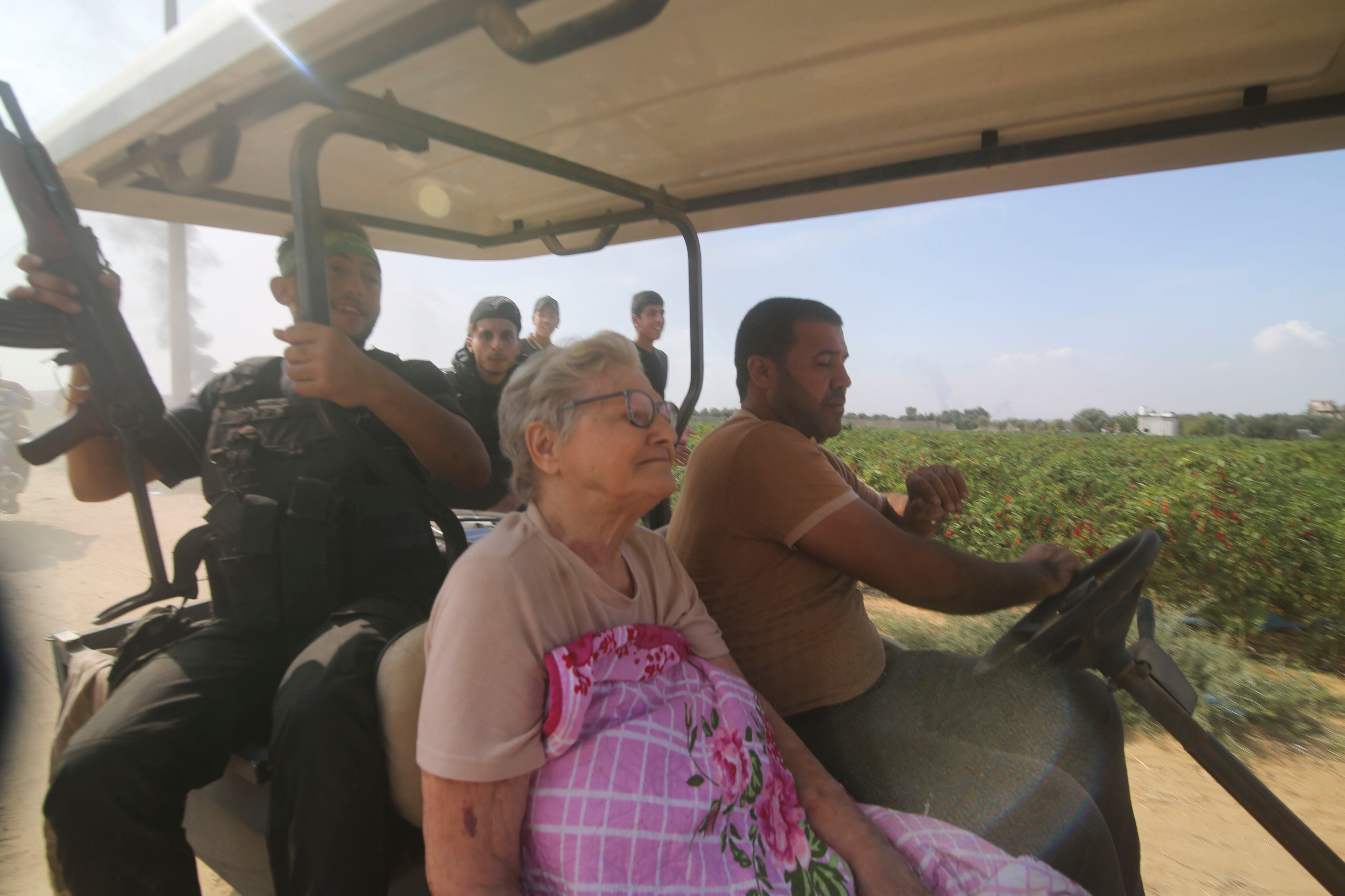 Palestinos se llevan a una anciana israelí capturada del kibbutz Kfar Azza a la Franja de Gaza, sábado 7 de octubre de 2023 (AP)