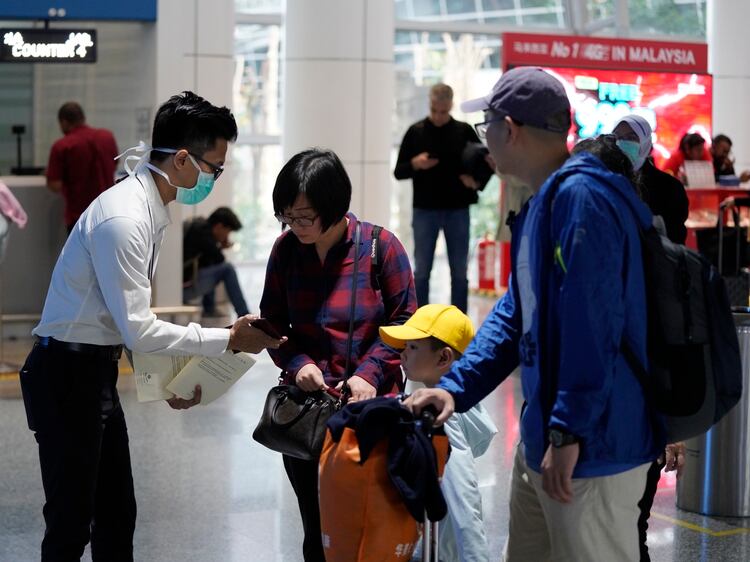 Los funcionarios de salud revisan a los pasajeros en el aeropuerto internacional de Kuala Lumpur en Sepang, Malasia, el martes 21 de enero de 2020. Países tanto en Asia-Pacífico como en otros lugares han iniciado controles de temperatura corporal en aeropuertos, estaciones de ferrocarril y autopistas con la esperanza de atraparlos. en riesgo de portar un nuevo coronavirus que ha enfermado a más de 200 personas en China. (Foto AP / Vincent Thian)