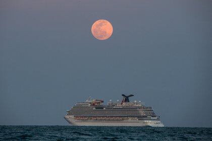 El crucero Carnival Vista navega durante una Luna Llena Super Rosa en Miami Beach, el 26 de abril de 2021 (Photo by CHANDAN KHANNA / AFP)