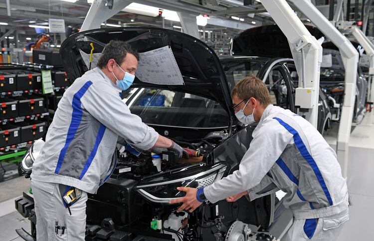 Max Bruehmann y Heiko Gruner usan una máscara protectora mientras trabajan en la línea de producción del Volkswagen eléctrico modelo ID.3 en Zwickau, Alemania, el 23 de abril de 2020 (Hendrik Schmidt/Pool vía REUTERS)