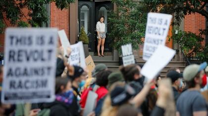 Una joven observa desde la puerta de su casa cómo se moviliza la multitud en rechazo al racismo, en Boston (REUTERS/Brian Snyder)