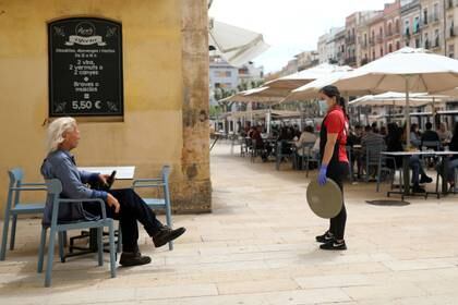 Un cliente es atendido en una terraza de Tarragona. La mitad del paÃ­s pasÃ³ a la Fase 1 de desconfinamiento, pero Madrid y Barcelona continÃºan con medidas estrictas (Reuters)