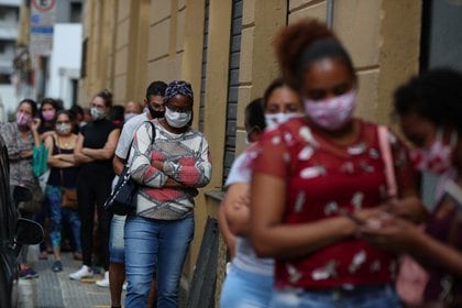 Un grupo de personas utilizando mascarillas esperan en fila para ingresar a un comercio durante la pandemia de coronavirus, en San Pablo, Brasil (REUTERS/Amanda Perobelli)