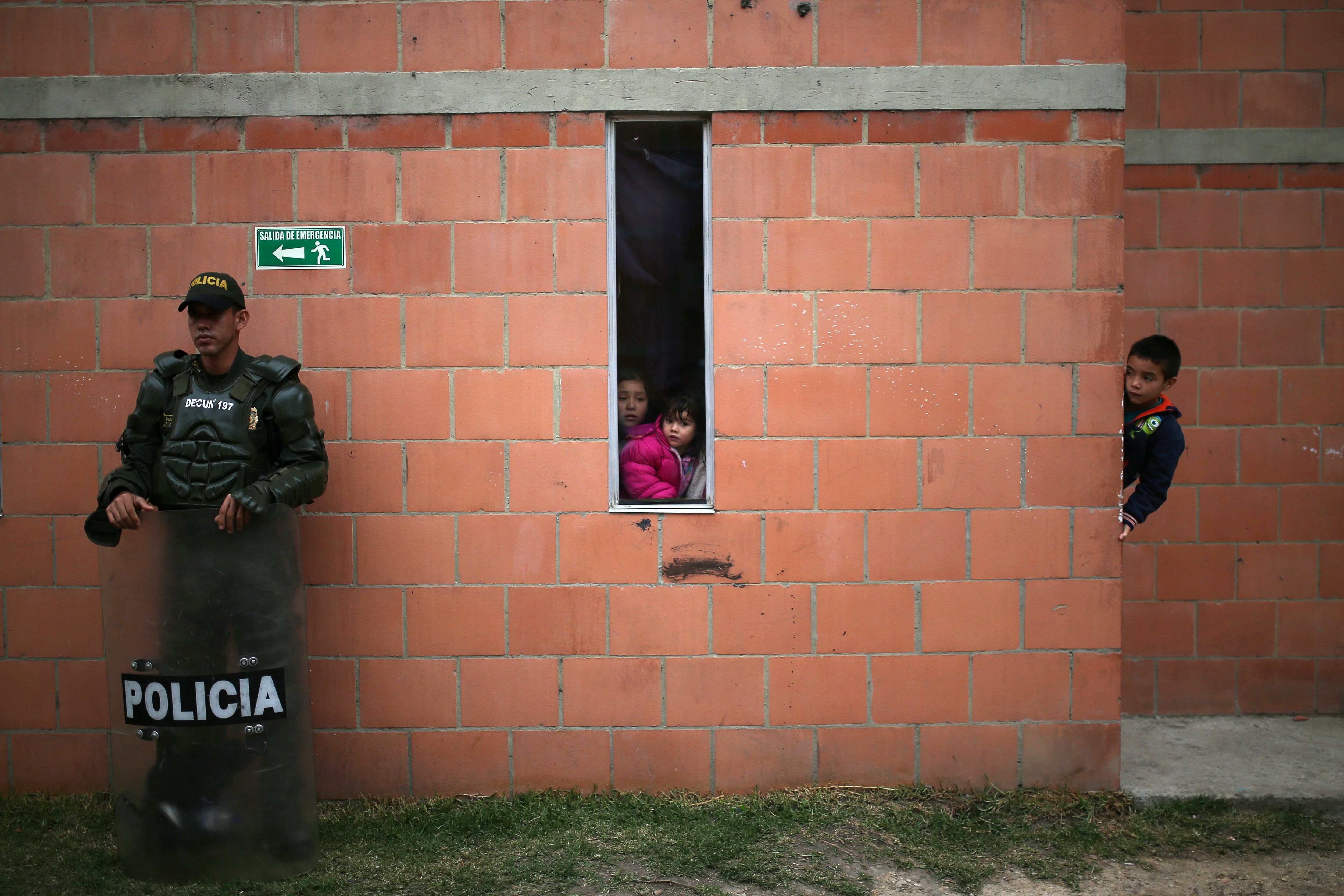 Un oficial de la policía antidisturbios hace guardia afuera de una vivienda precaria, en medio del brote de la enfermedad coronavirus (COVID-19) en Soacha, Colombia,