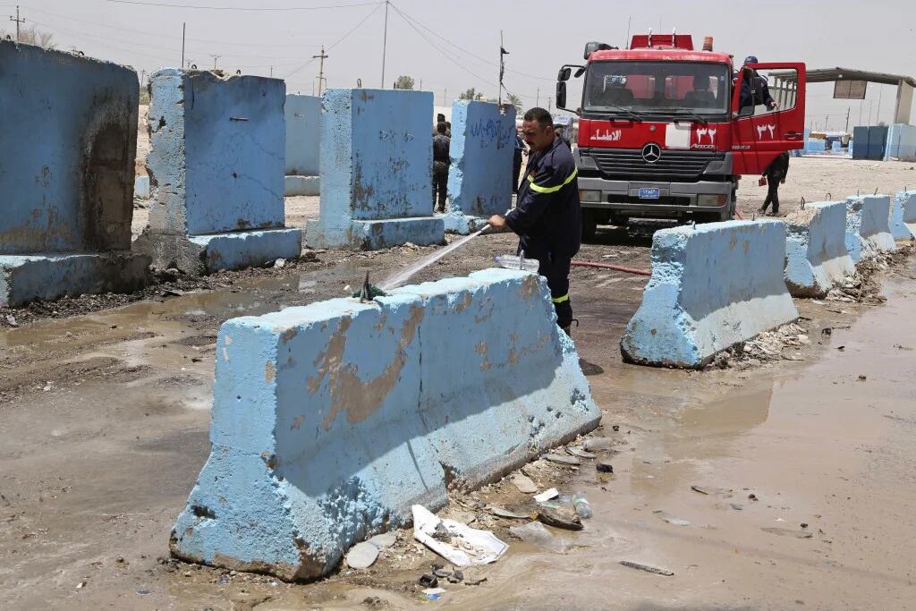Un bombero limpia el lugar de un atentado con coche bomba en Bagdad (AP)