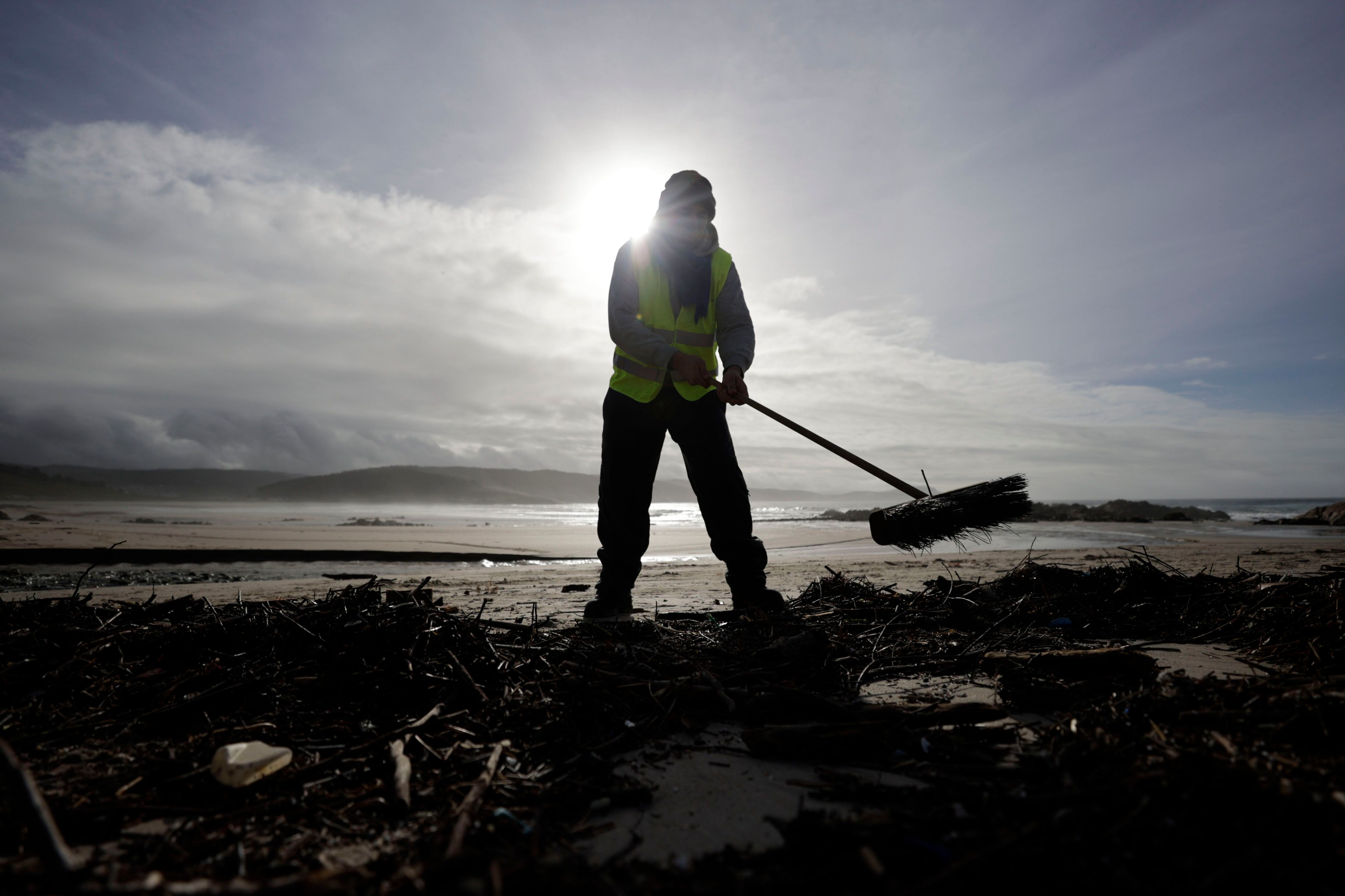 Un operario limpiaba la playa de Nemiña, en el concello coruñés de Muxía, donde continúan las labores de limpieza de zonas costeras afectadas por la contaminación de pellets de plástico después de que el mercante Toconao perdiera parte de su carga el pasado diciembre. EFE/Cabalar