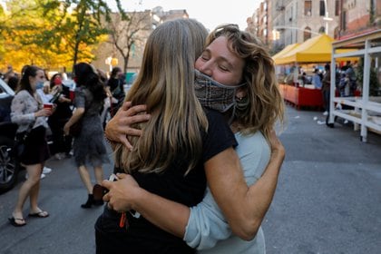 Dos mujeres se abrazan ante la victoria de Joe Biden en el barrio de Alphabet City de Manhattan, en Nueva York. REUTERS/Andrew Kelly