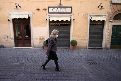 Una mujer pasa frente a un café cerrado en Roma. A partir del lunes, todas las tiendas no esenciales deberán permanecer cerradas (REUTERS/Yara Nardi)