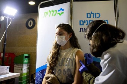 Una joven recibe una vacuna contra el COVID-19 en un centro sanitario temporario en un estadio en Jerusalén, Israel, 4 de febrero de 2021. REUTERS/Ronen Zvulun