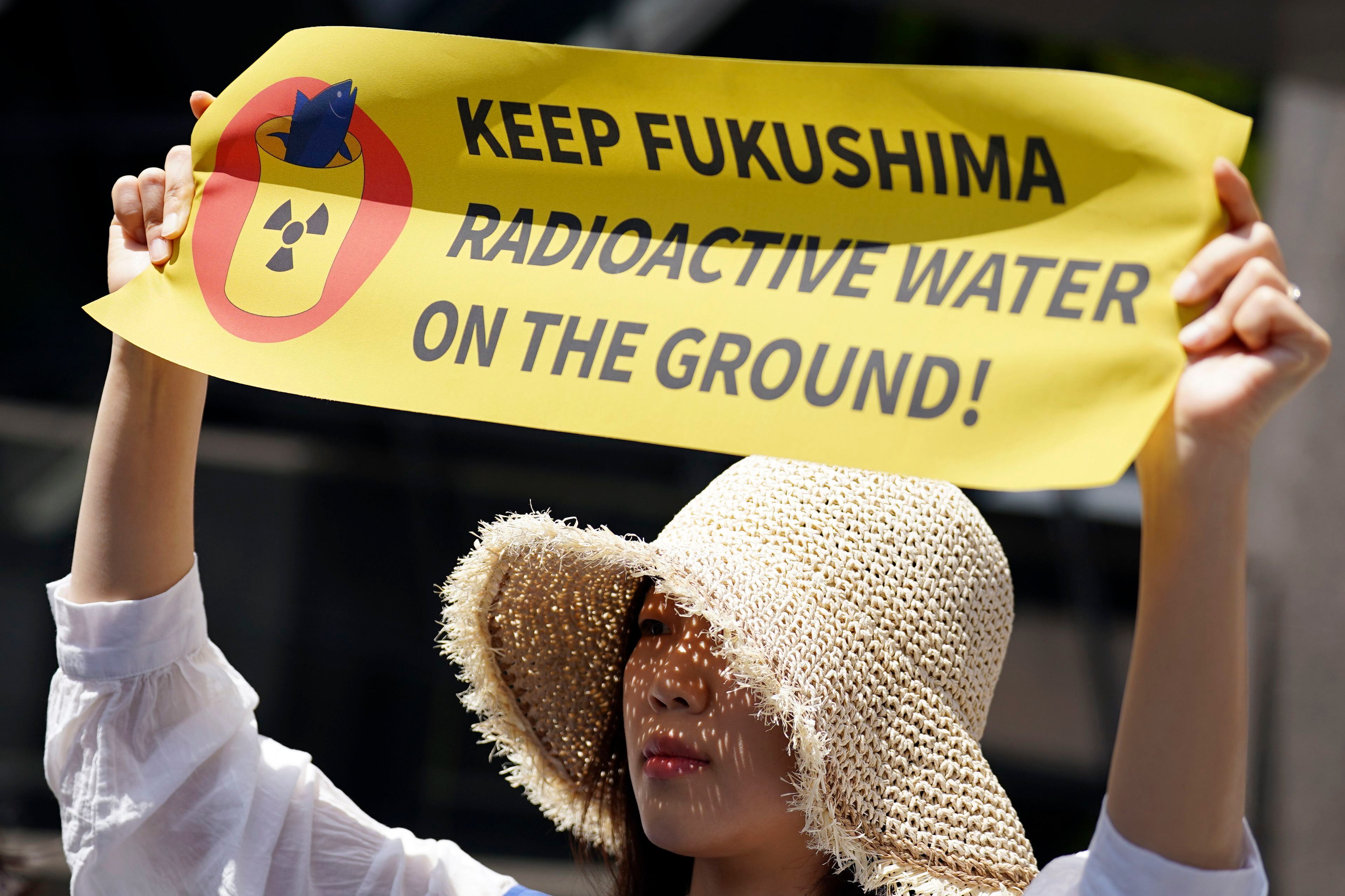 Una manifestante sostiene un cartel durante una protesta ante la sede de Tokyo Electric Power Company Holdings (TEPCO) el martes 16 de mayo de 2023 en Tokio. Docenas de activistas contrarios a la energía nuclear se manifestaron el martes para pedir que Japón abandone su plan de verter al mar agua tratada pero aún radiactiva de una central nuclear dañada por un tsunami, un proceso que podría comenzar este verano. El cartel dice "¡Mantengan el agua radiactiva de Fukushima en tierra!". (AP Foto/Eugene Hoshiko)