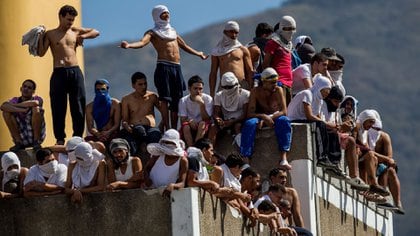 Presos venezolanos escalan un muro para tratar de llegar al lado de la prisión controlado por los pranes. (EFE)