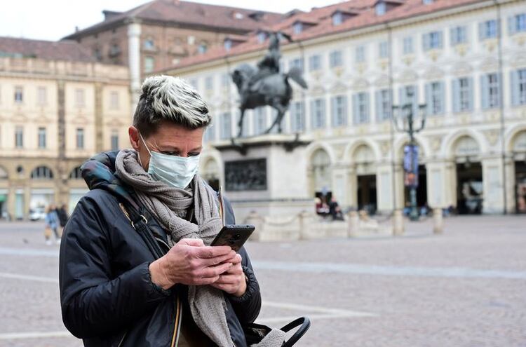 Una mujer que lleva una máscara protectora usa su teléfono móvil, mientras un brote de coronavirus continúa creciendo en el norte de Italia, en Turín (Italia), el 27 de febrero de 2020. (Reuters)