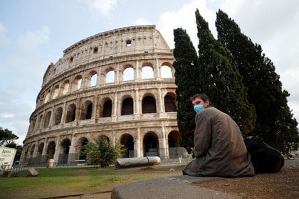 Un hombre usa una máscara protectora mientras se sienta cerca del Coliseo, mientras continúa la propagación de la enfermedad del coronavirus (COVID-19), en Roma, Italia. 12 de noviembre de 2020. REUTERS/Guglielmo Mangiapane