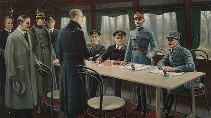 Una postal de la época representando la firma del armisticio. De pie y frente a la mesa se encuentra el jefe de la delegación alemana, Matthias Erzberger. También de pie y en uniforme, el mariscal francés Ferdinannd Foch